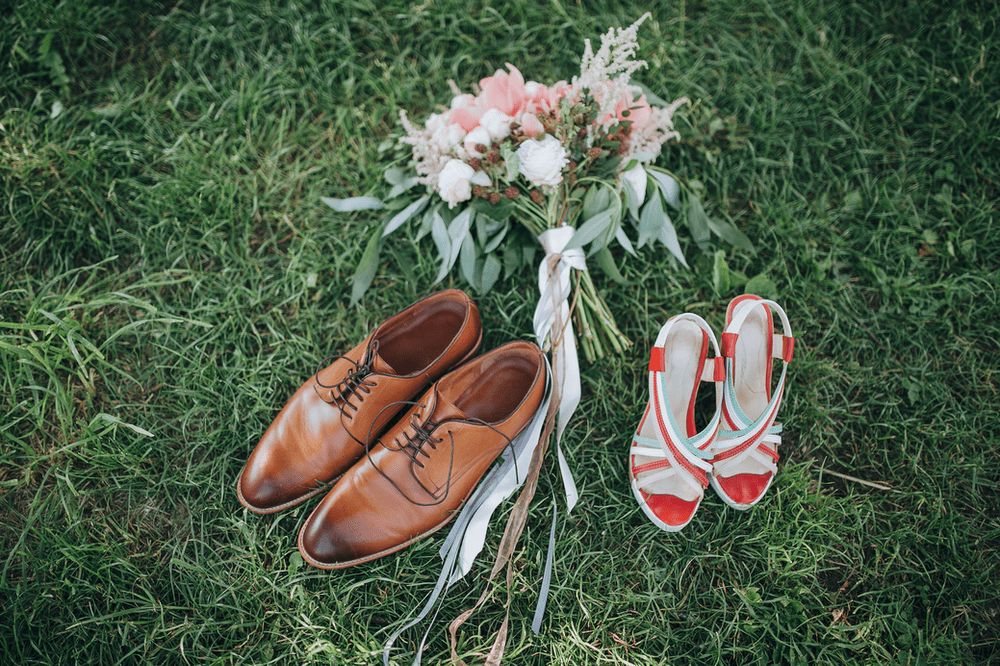 a pair of his and hers shoes next to a bouquet of flowers